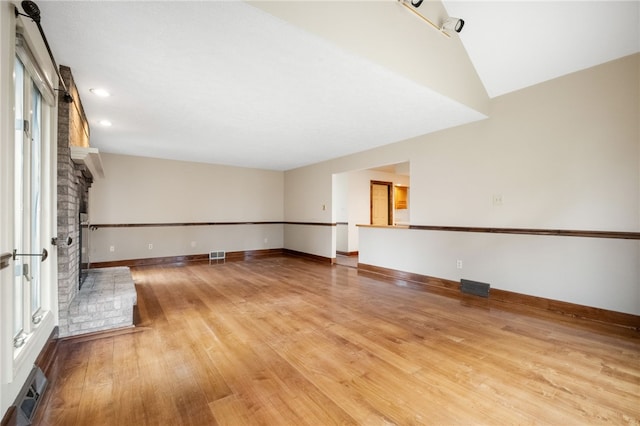 spare room with visible vents, a brick fireplace, baseboards, and light wood-style floors