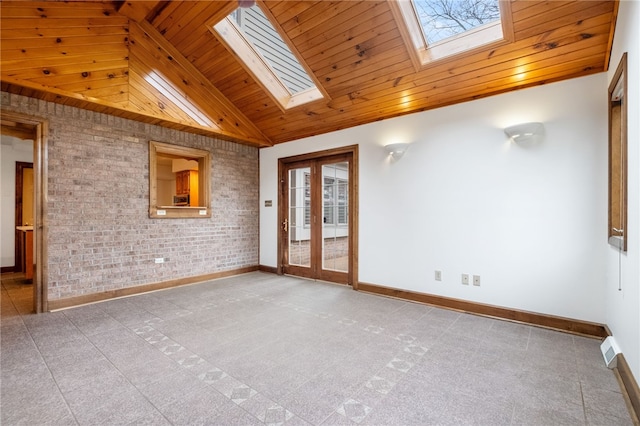 empty room featuring brick wall, baseboards, wood ceiling, french doors, and a skylight