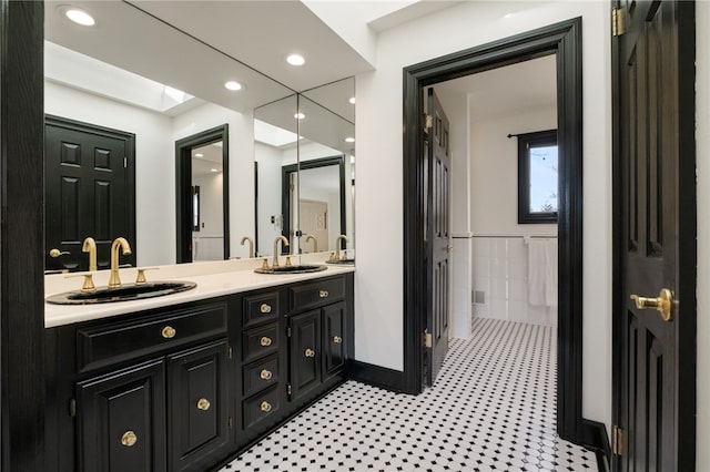 bathroom with double vanity, recessed lighting, tile walls, and a sink