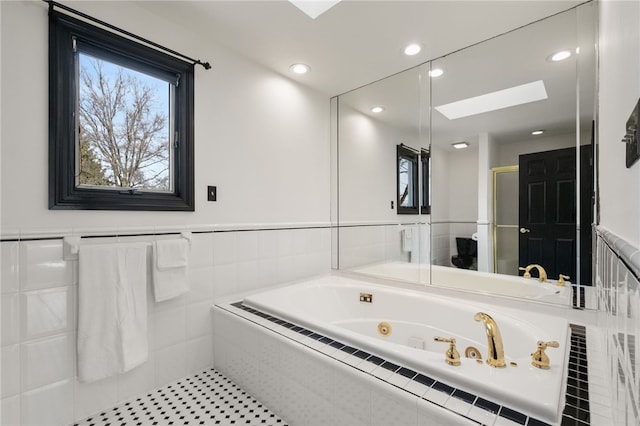 full bathroom with a whirlpool tub, wainscoting, recessed lighting, a stall shower, and a skylight