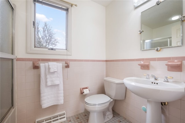 bathroom with tile patterned floors, visible vents, a wainscoted wall, toilet, and tile walls