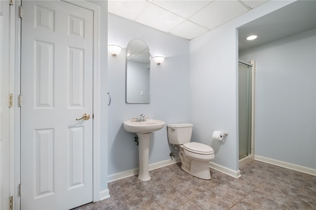 bathroom with toilet, baseboards, a stall shower, and a drop ceiling