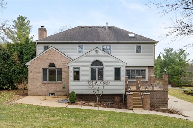 back of property featuring a yard, brick siding, a chimney, and a shingled roof