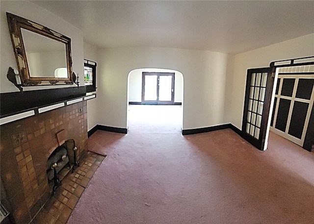 unfurnished living room with dark colored carpet, baseboards, and arched walkways