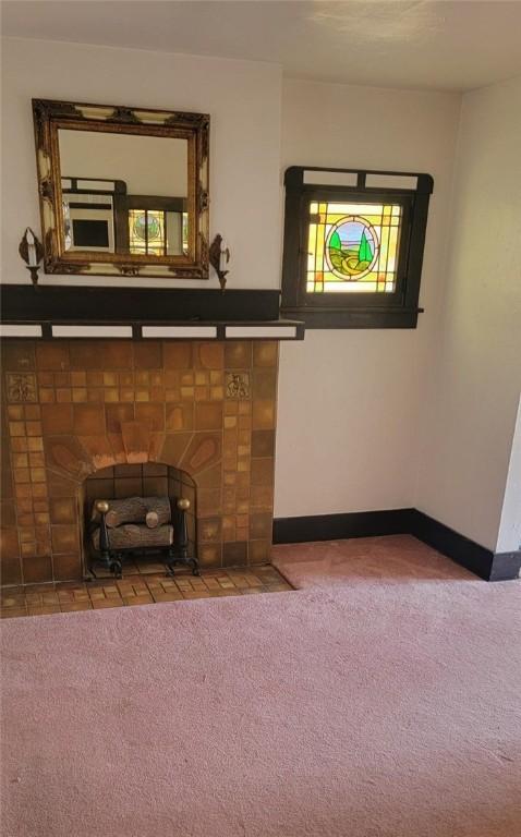 unfurnished living room featuring baseboards, carpet, and a tiled fireplace