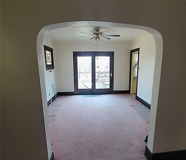 spare room with carpet, a ceiling fan, arched walkways, and baseboards