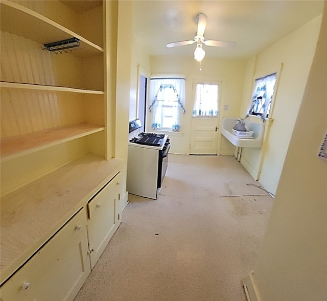 kitchen with light carpet, white gas stove, white cabinets, light countertops, and ceiling fan