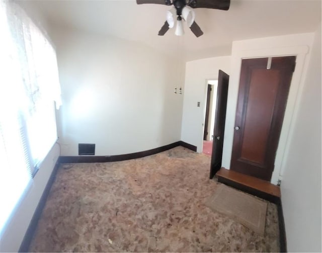 carpeted spare room featuring visible vents, baseboards, and a ceiling fan