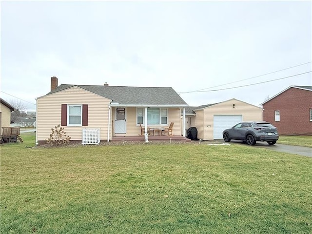 single story home featuring aphalt driveway, covered porch, a detached garage, and a front yard