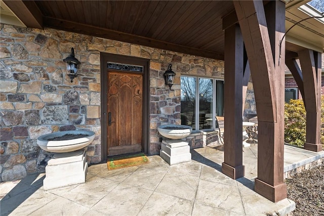 doorway to property featuring stone siding and a patio