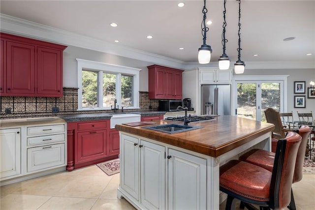 kitchen featuring tasteful backsplash, high end refrigerator, a healthy amount of sunlight, and a sink