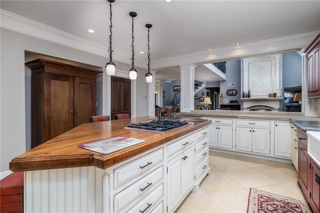 kitchen with a center island, crown molding, stainless steel gas cooktop, butcher block countertops, and ornate columns