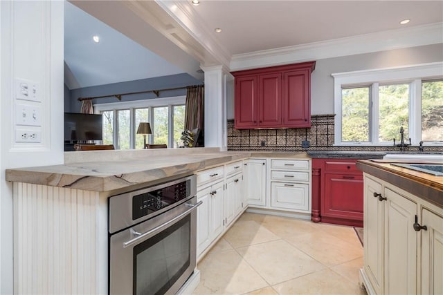 kitchen featuring light tile patterned floors, a sink, ornamental molding, oven, and tasteful backsplash