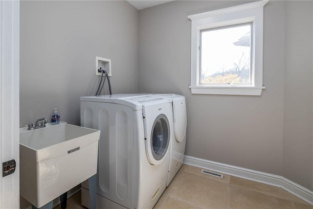 washroom with a sink, visible vents, laundry area, and washer and clothes dryer