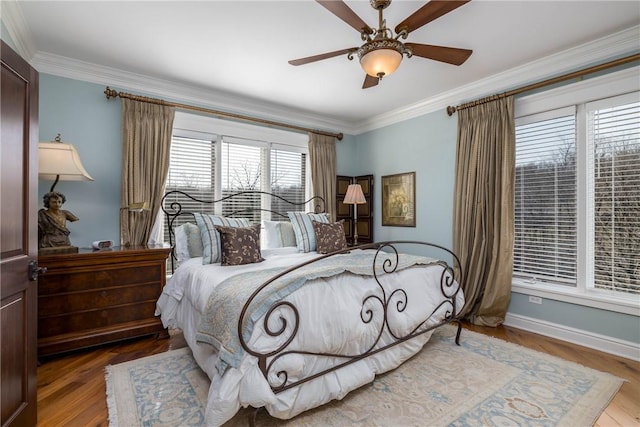 bedroom featuring baseboards, wood finished floors, ornamental molding, and a ceiling fan