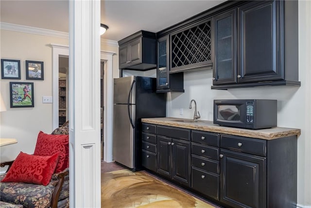 kitchen with ornamental molding, a sink, freestanding refrigerator, black microwave, and light countertops