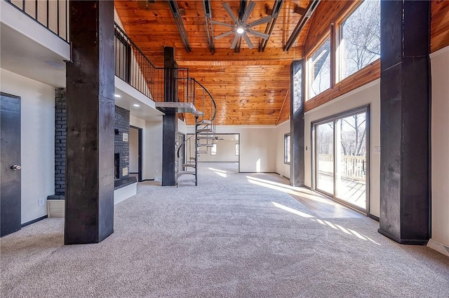 interior space featuring high vaulted ceiling, wood ceiling, carpet, a brick fireplace, and stairs