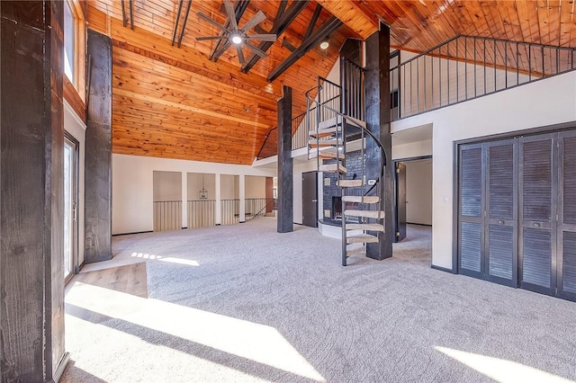 unfurnished living room with beam ceiling, carpet flooring, wooden ceiling, high vaulted ceiling, and a ceiling fan