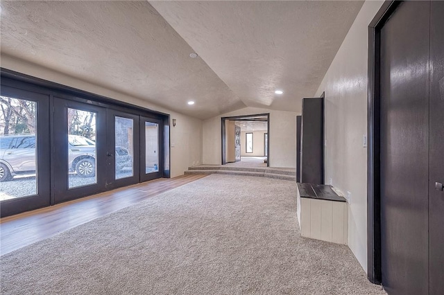 spare room with carpet, lofted ceiling, recessed lighting, french doors, and a textured ceiling