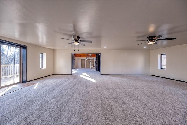 spare room with baseboards, plenty of natural light, light colored carpet, and ceiling fan