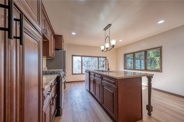 kitchen featuring a sink, light wood-type flooring, appliances with stainless steel finishes, and a breakfast bar