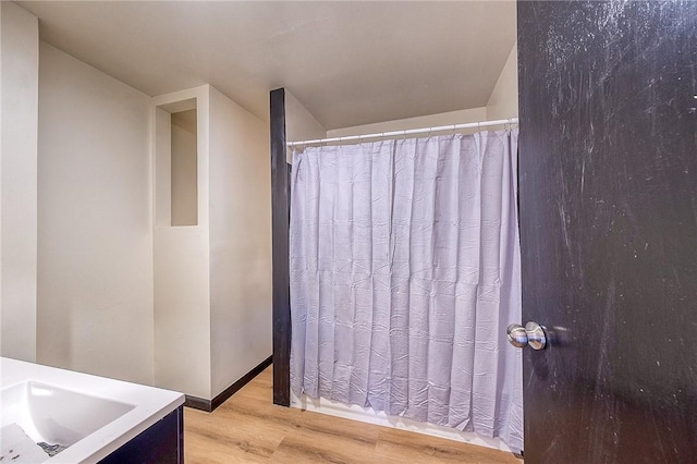 bathroom with vanity, curtained shower, and wood finished floors