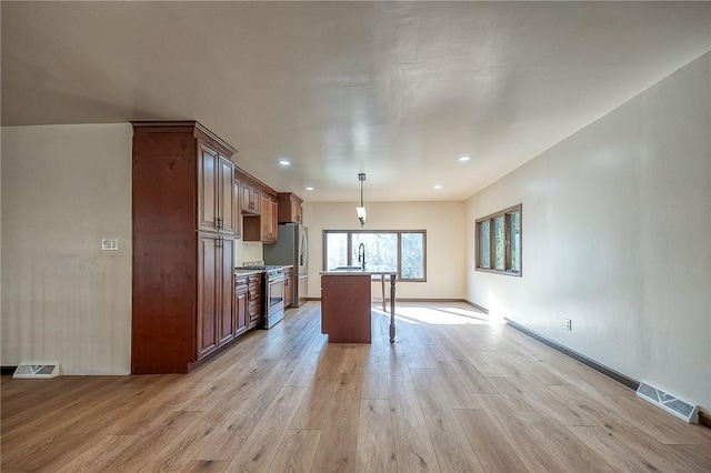 kitchen featuring hanging light fixtures, light wood finished floors, visible vents, and appliances with stainless steel finishes