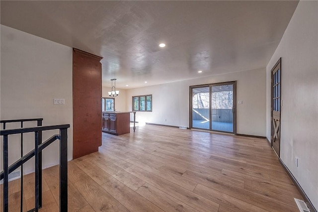 unfurnished room with light wood finished floors, visible vents, baseboards, recessed lighting, and a notable chandelier