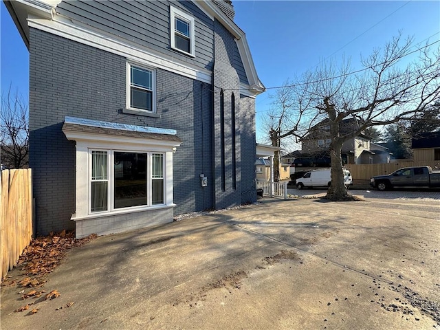 view of side of home with fence and brick siding