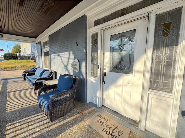 property entrance with a porch and brick siding