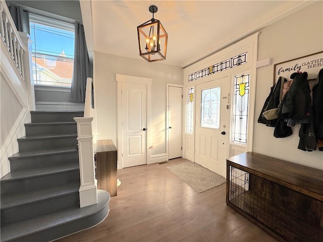 entrance foyer featuring a chandelier, stairway, baseboards, and wood finished floors