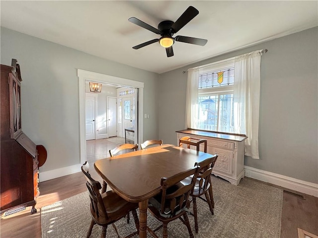 dining area featuring a ceiling fan, light wood-style floors, and baseboards