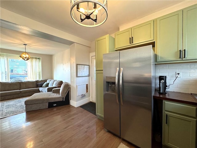 kitchen with a notable chandelier, light wood-style flooring, stainless steel refrigerator with ice dispenser, green cabinetry, and decorative backsplash