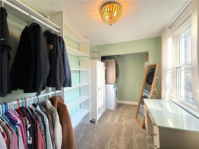 walk in closet with stacked washer and dryer and carpet