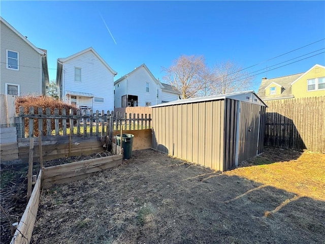 view of yard with a storage unit, an outbuilding, a fenced backyard, a residential view, and a garden