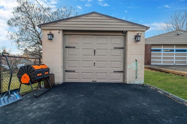 detached garage featuring driveway and fence