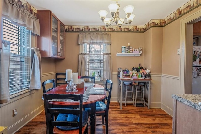 dining space with an inviting chandelier, wood finished floors, and wainscoting