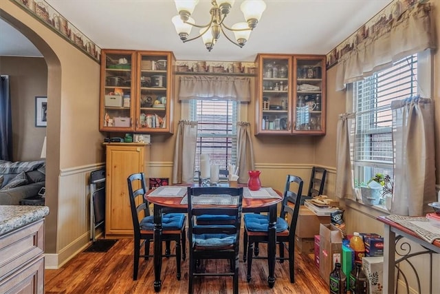 dining room featuring arched walkways, a wainscoted wall, a notable chandelier, and dark wood-style floors