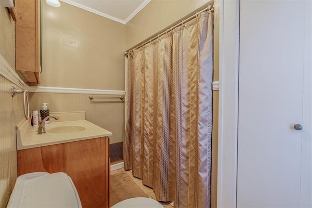 bathroom with vanity, a shower with curtain, a wainscoted wall, crown molding, and toilet