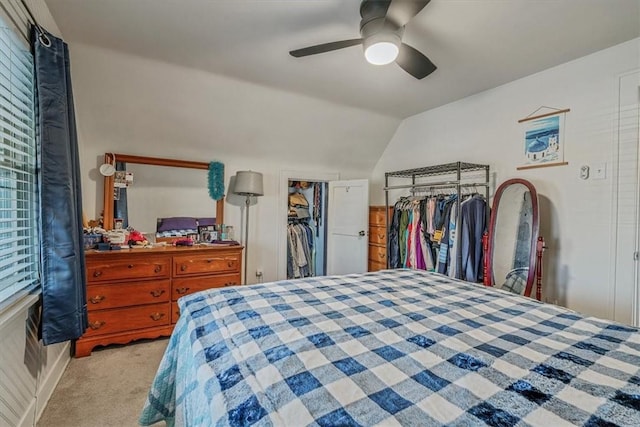 bedroom featuring a walk in closet, light colored carpet, ceiling fan, and vaulted ceiling