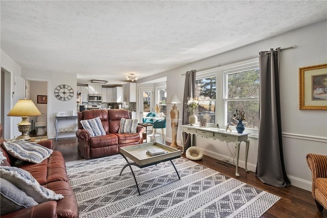 living room featuring baseboards, a textured ceiling, and wood finished floors