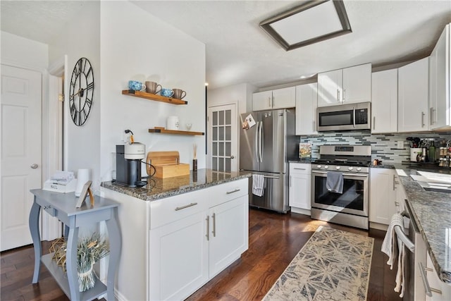 kitchen featuring dark wood-type flooring, dark stone counters, decorative backsplash, appliances with stainless steel finishes, and white cabinetry