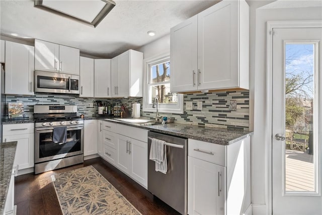 kitchen featuring a sink, dark wood-style floors, white cabinetry, appliances with stainless steel finishes, and decorative backsplash