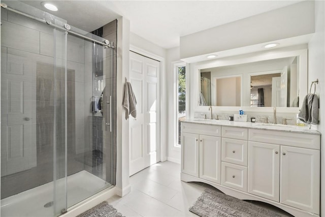 full bath with a sink, a stall shower, double vanity, and tile patterned floors