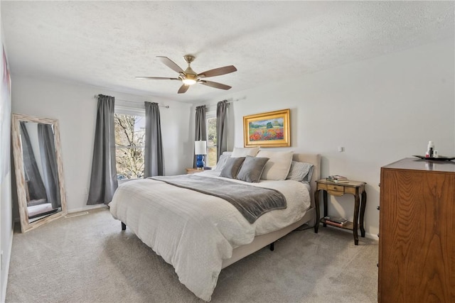 bedroom featuring light colored carpet, ceiling fan, and a textured ceiling