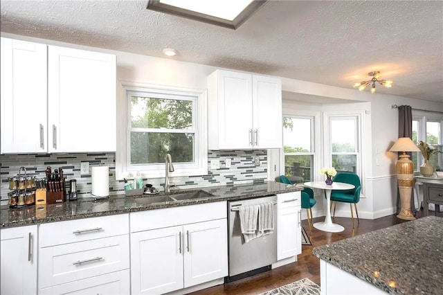 kitchen featuring dark wood finished floors, dishwasher, dark stone counters, white cabinets, and a sink