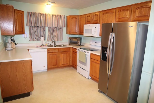 kitchen featuring white appliances, light countertops, brown cabinets, and a sink