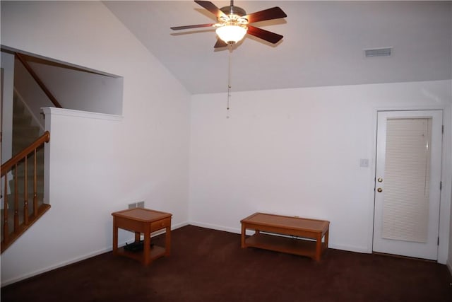 carpeted empty room with baseboards, visible vents, ceiling fan, stairs, and vaulted ceiling