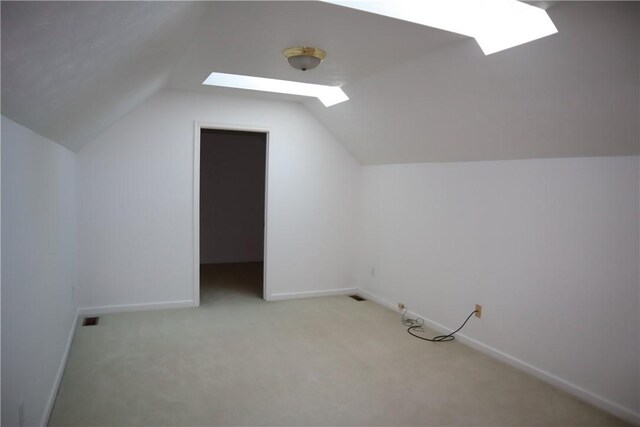 additional living space featuring baseboards, visible vents, lofted ceiling, and light carpet