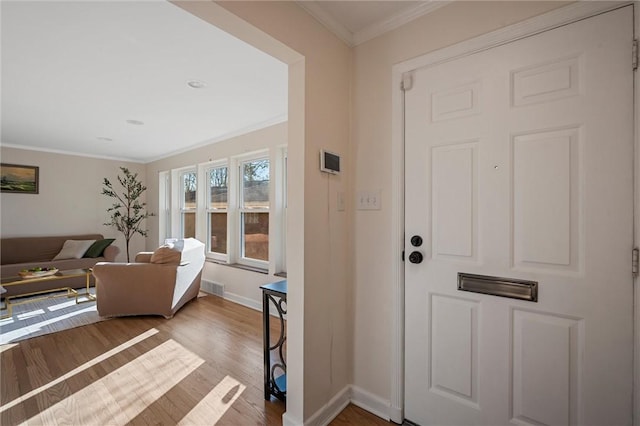 entrance foyer featuring visible vents, baseboards, wood finished floors, and crown molding